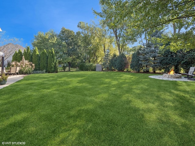 view of yard with a patio, a fire pit, and a shed