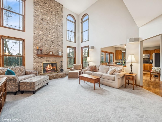 carpeted living room with a healthy amount of sunlight, a fireplace, and high vaulted ceiling