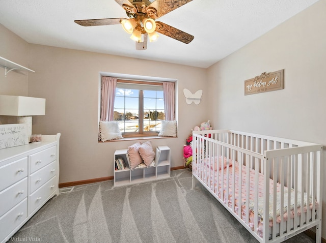 bedroom with ceiling fan, a crib, and carpet