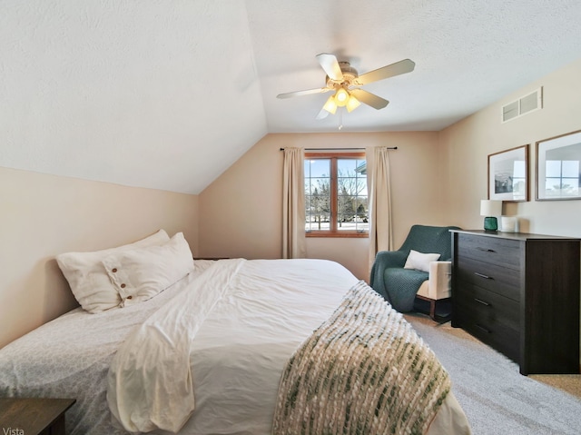 carpeted bedroom with a textured ceiling, ceiling fan, and vaulted ceiling