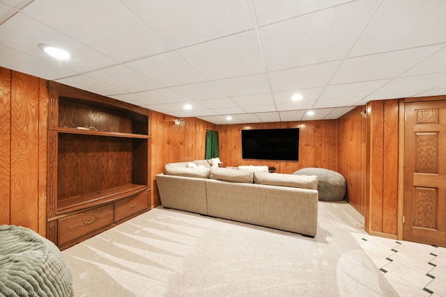 living room featuring a paneled ceiling, wooden walls, and light carpet