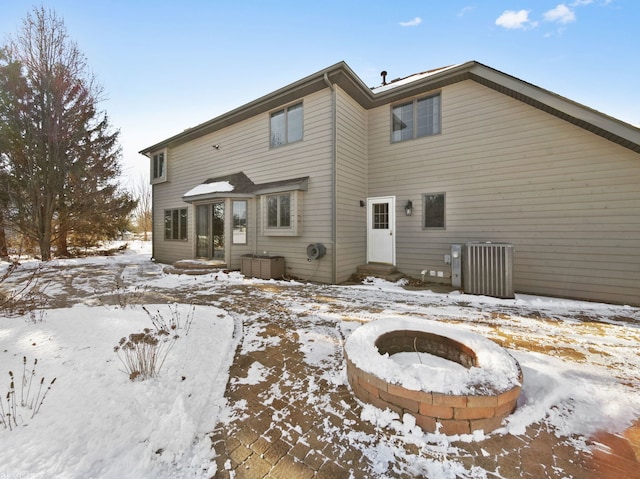 snow covered rear of property with central AC and an outdoor fire pit