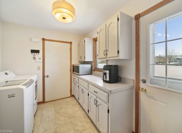 laundry area with independent washer and dryer and cabinets