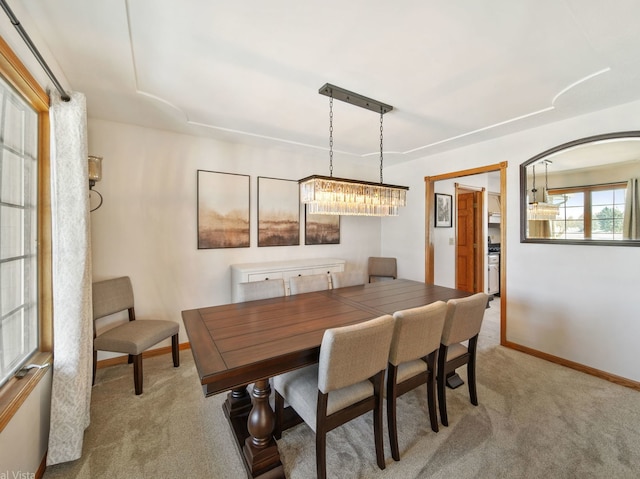 dining space featuring a notable chandelier and light carpet