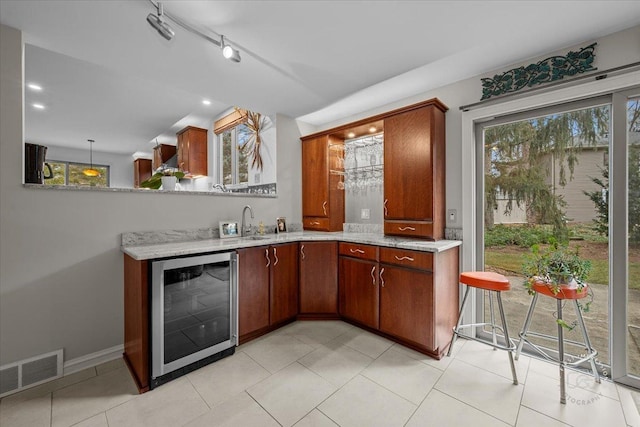 bar with decorative light fixtures, beverage cooler, and sink