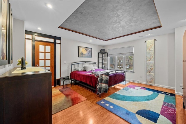 bedroom featuring light hardwood / wood-style floors and a tray ceiling