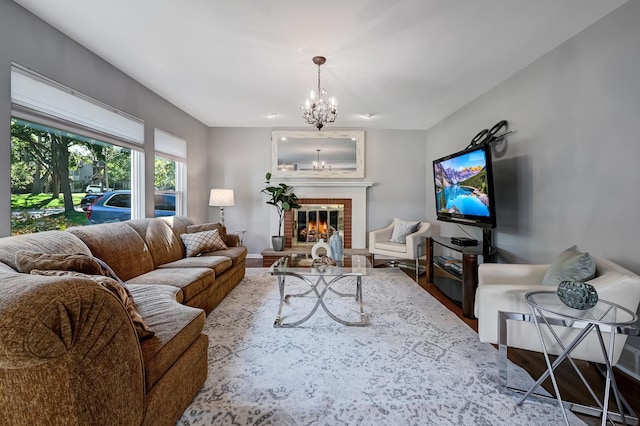 living room with a brick fireplace, wood-type flooring, and a notable chandelier