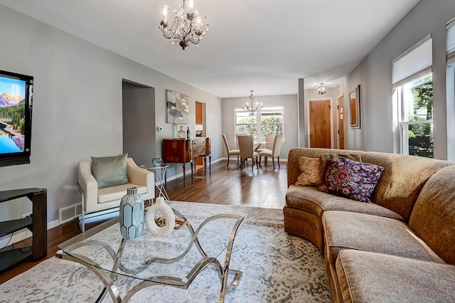 living room with a healthy amount of sunlight, dark hardwood / wood-style floors, and a notable chandelier