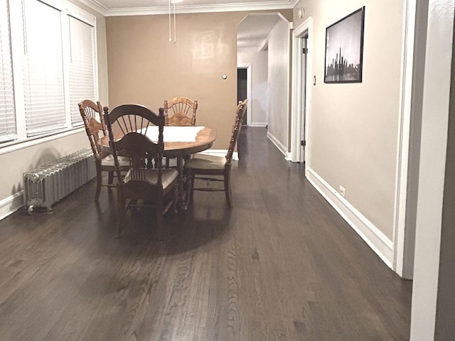 dining space with dark hardwood / wood-style flooring, crown molding, and radiator