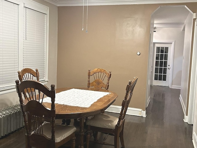 dining space featuring dark hardwood / wood-style floors, radiator heating unit, ornamental molding, and a baseboard radiator