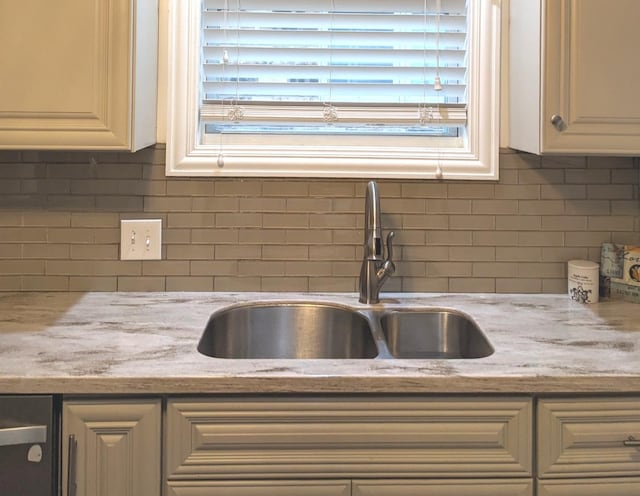 room details with backsplash, light stone countertops, and sink