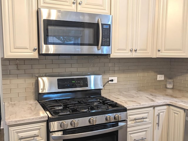 kitchen with appliances with stainless steel finishes, tasteful backsplash, and light stone counters