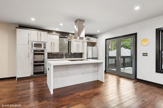 kitchen featuring dark hardwood / wood-style flooring, tasteful backsplash, island range hood, stainless steel appliances, and a kitchen island