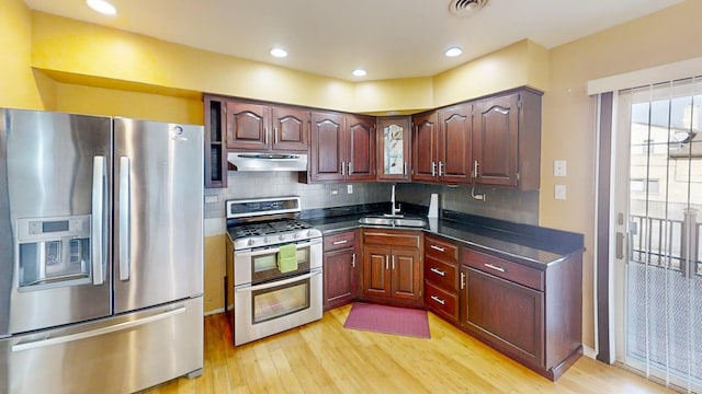 kitchen with backsplash, sink, stainless steel appliances, and light hardwood / wood-style floors