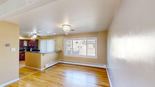 kitchen with kitchen peninsula, a breakfast bar, light hardwood / wood-style floors, and baseboard heating