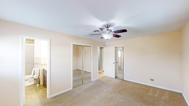 unfurnished bedroom featuring ceiling fan, light colored carpet, and ensuite bath