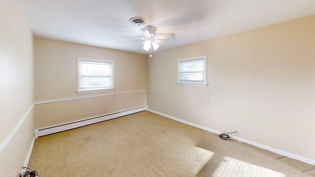 carpeted spare room with baseboard heating, ceiling fan, and plenty of natural light