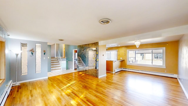 unfurnished living room featuring baseboard heating, hardwood / wood-style floors, and a notable chandelier