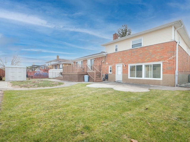 rear view of house featuring a storage unit, a patio area, a yard, and a wooden deck