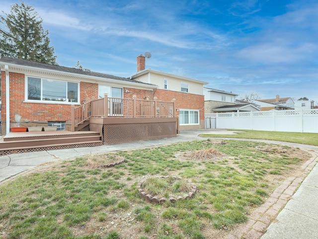 rear view of house featuring a lawn and a wooden deck