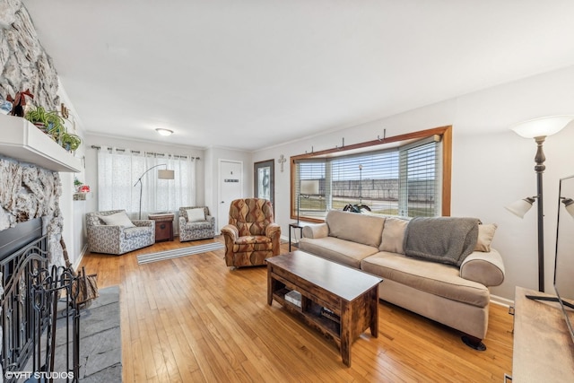 living room with light hardwood / wood-style flooring, crown molding, and a fireplace