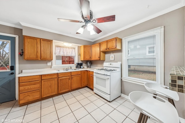 kitchen with ceiling fan, sink, light tile patterned floors, white gas range oven, and ornamental molding