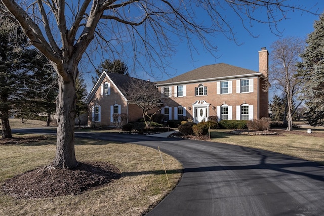 colonial-style house featuring a front lawn