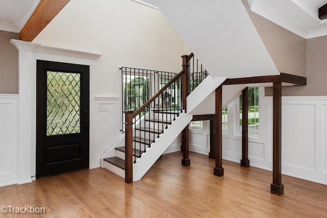 entryway featuring beamed ceiling, ornamental molding, and light wood-type flooring