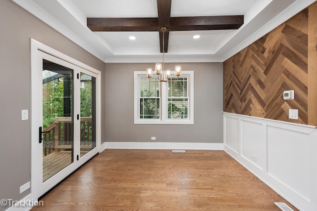 unfurnished dining area featuring a chandelier, hardwood / wood-style floors, and beamed ceiling