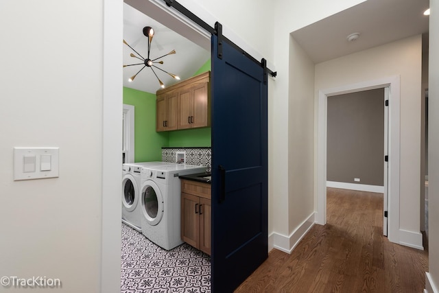 clothes washing area with cabinets, an inviting chandelier, dark hardwood / wood-style floors, a barn door, and washing machine and dryer