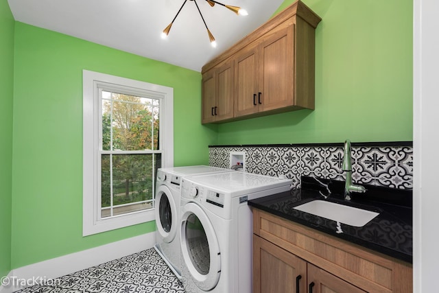 washroom featuring washer and dryer, cabinets, sink, and a chandelier