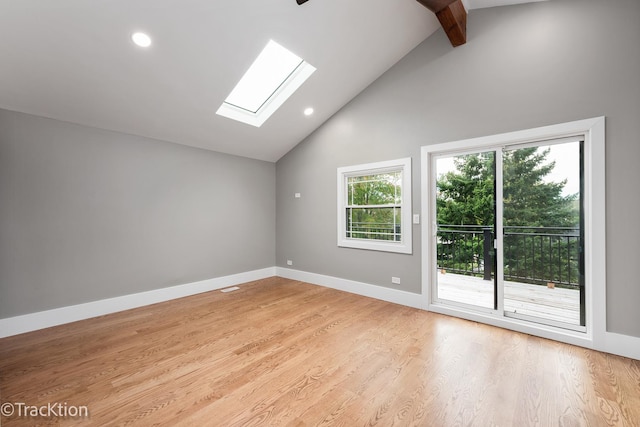 empty room with beamed ceiling, light wood-type flooring, high vaulted ceiling, and a skylight