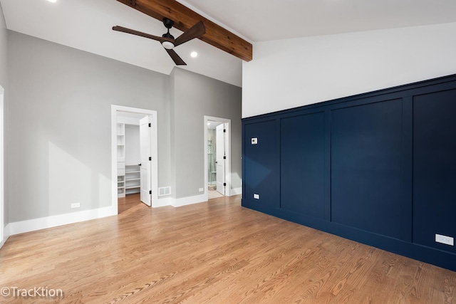 unfurnished bedroom featuring a walk in closet, ceiling fan, beam ceiling, light hardwood / wood-style floors, and a closet