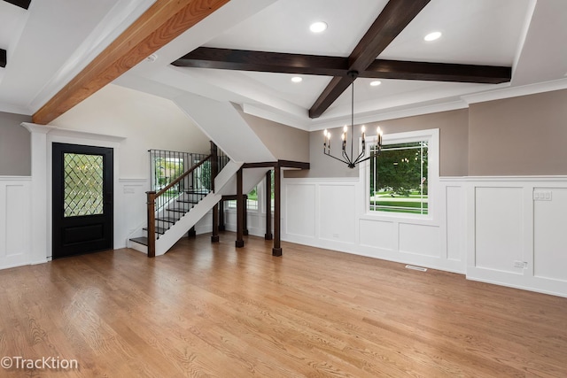 entrance foyer with beam ceiling, light hardwood / wood-style floors, an inviting chandelier, and crown molding