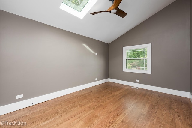 spare room with vaulted ceiling with skylight, ceiling fan, and light wood-type flooring