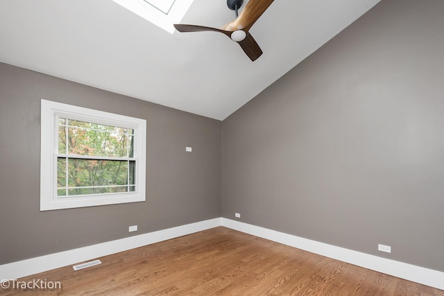 spare room with light hardwood / wood-style flooring, ceiling fan, and lofted ceiling with skylight