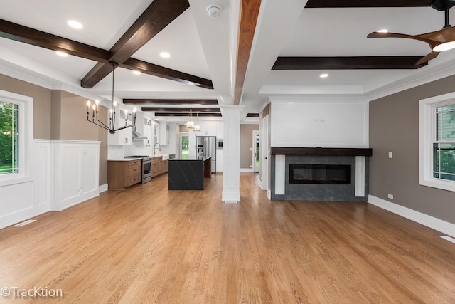 unfurnished living room featuring decorative columns, sink, beamed ceiling, and light hardwood / wood-style floors