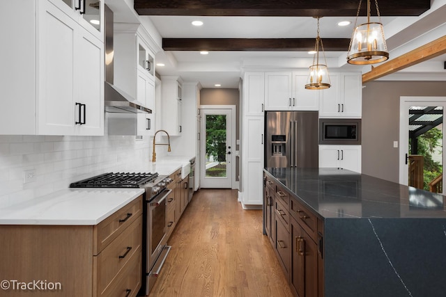 kitchen with white cabinetry, wall chimney range hood, light hardwood / wood-style floors, dark stone counters, and high end appliances