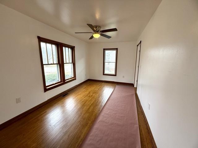 empty room with dark hardwood / wood-style flooring and ceiling fan