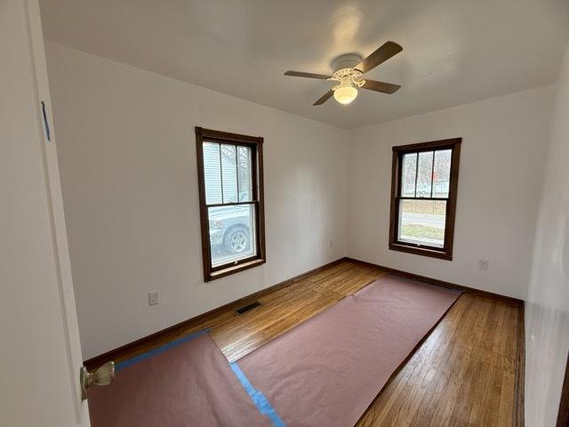 empty room with hardwood / wood-style floors and ceiling fan