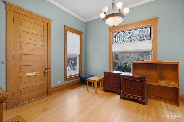 living area with a notable chandelier, ornamental molding, and light hardwood / wood-style flooring