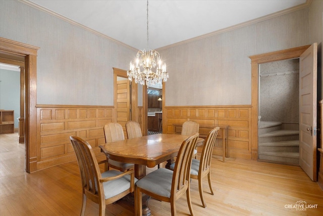 dining space with a chandelier, light wood-type flooring, and ornamental molding