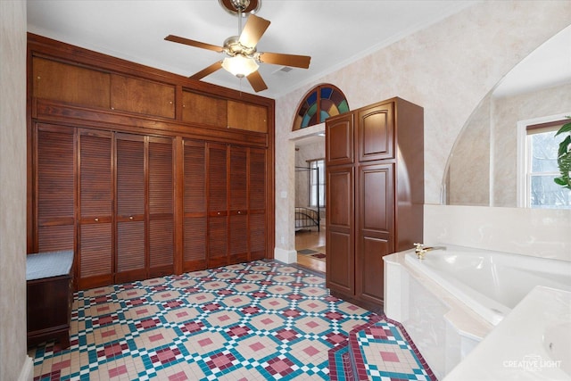 bathroom with a bathing tub, ceiling fan, and crown molding