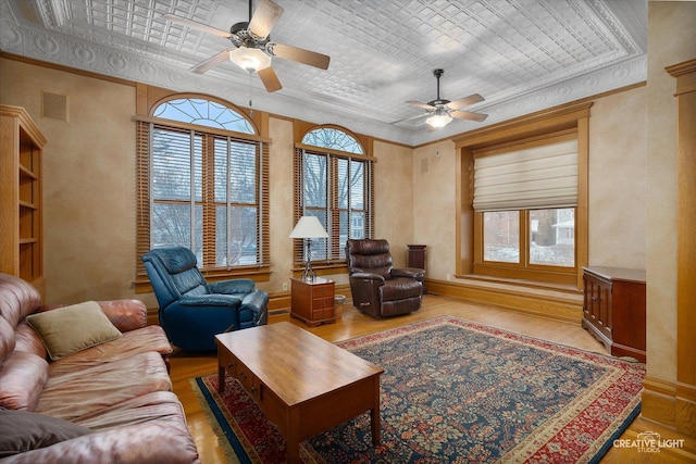 living room with ceiling fan, hardwood / wood-style floors, crown molding, and built in features