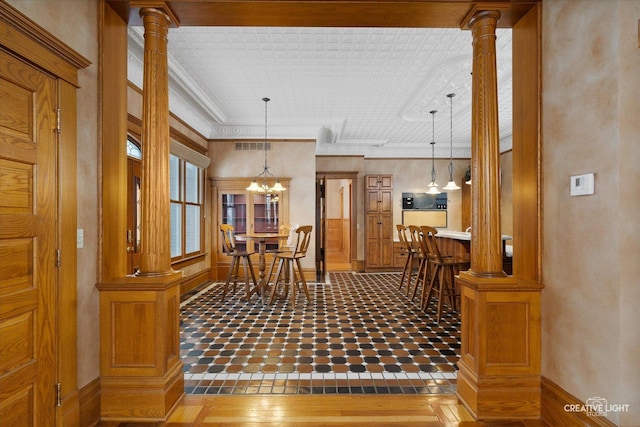 tiled dining room featuring decorative columns and an inviting chandelier