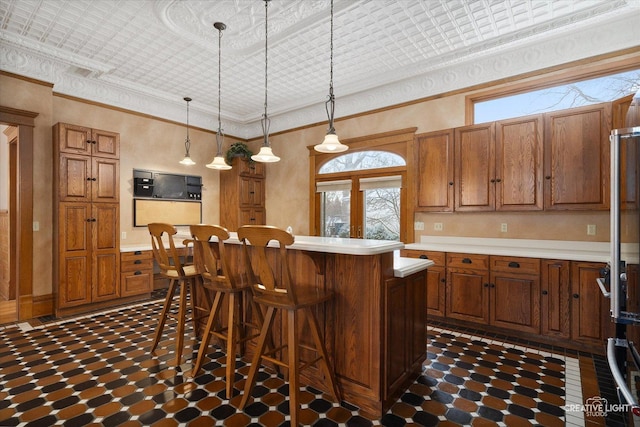 kitchen featuring french doors, ornamental molding, a breakfast bar, pendant lighting, and a center island