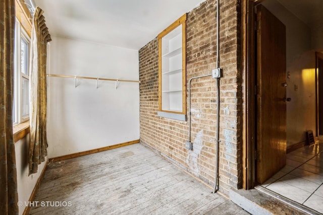 interior space featuring built in shelves, brick wall, and hardwood / wood-style flooring