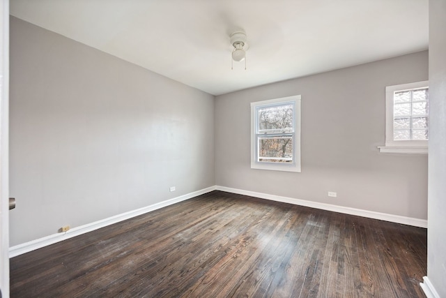 spare room with dark wood-type flooring, ceiling fan, and a healthy amount of sunlight