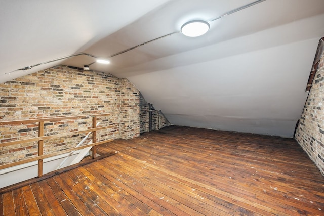 bonus room with dark hardwood / wood-style flooring, brick wall, and vaulted ceiling