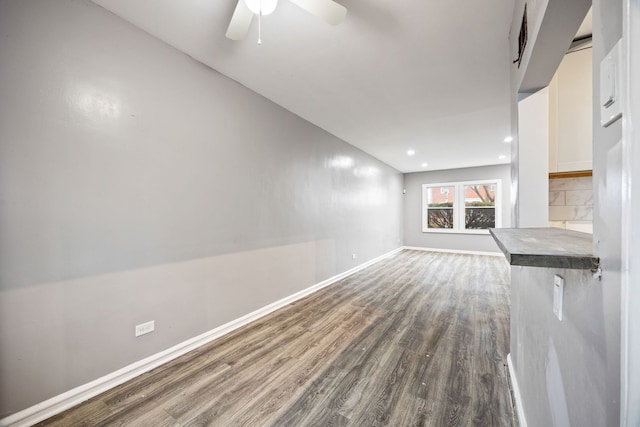 unfurnished living room featuring ceiling fan and dark hardwood / wood-style flooring